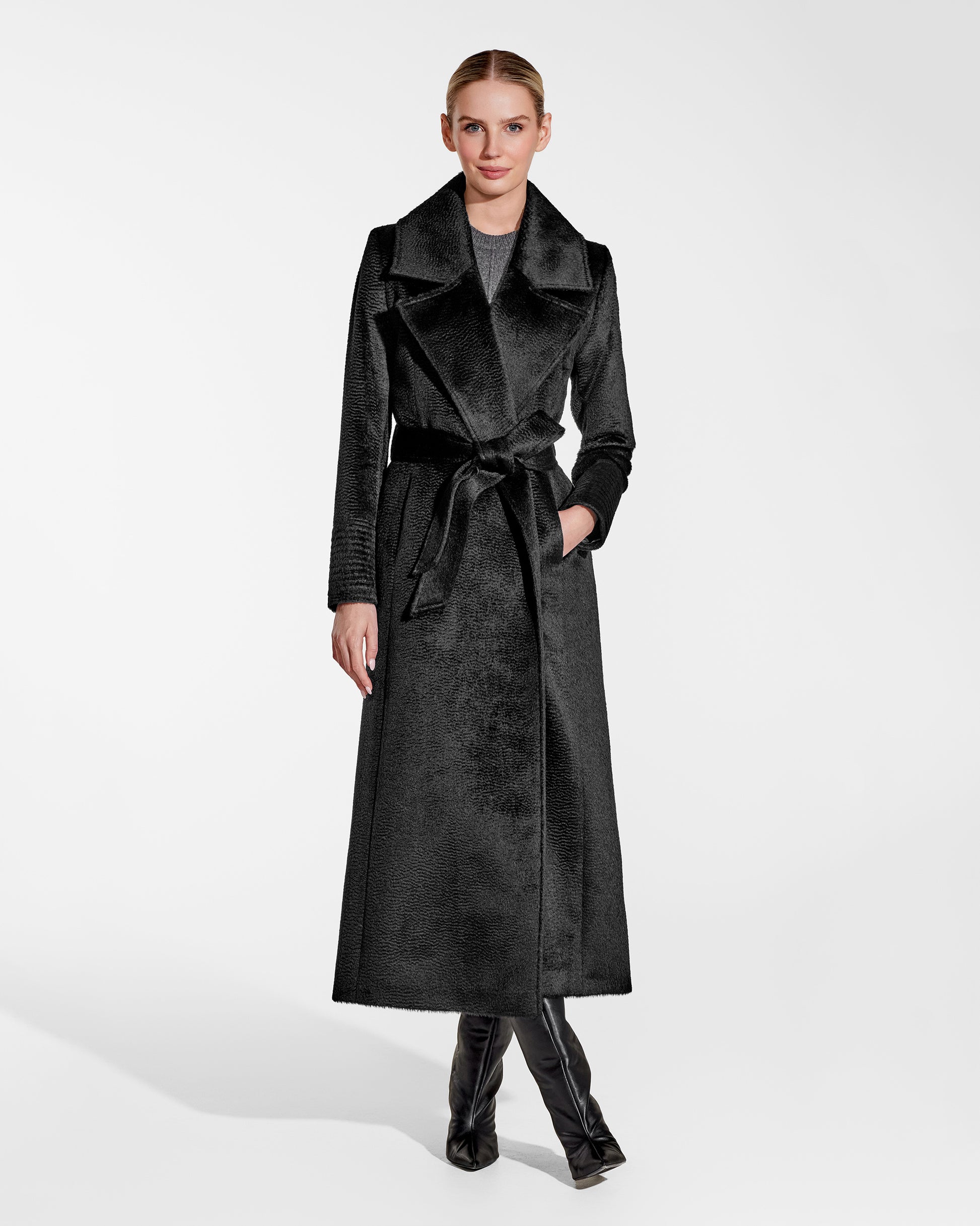 Front view of model wearing a Sentaler black maxi coat made of suri alpaca wool, with a notched collar, worn belted.