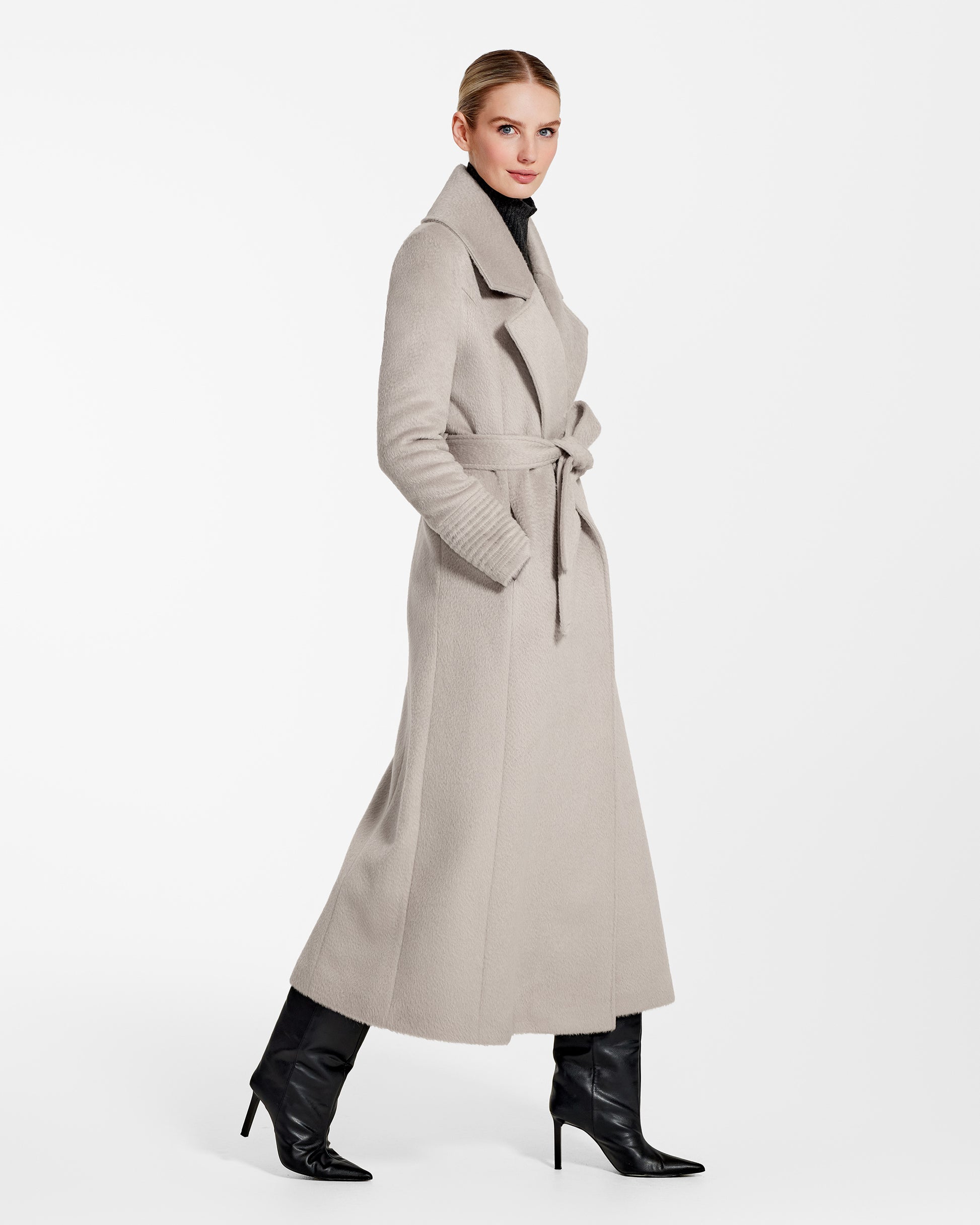 Side view of model wearing a Sentaler sand maxi coat made of suri alpaca wool, with a notched collar, worn belted.