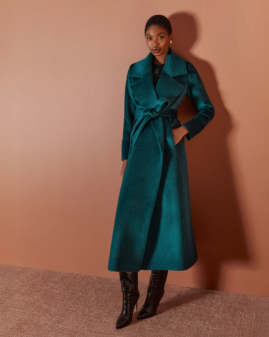 Front view of model wearing a Sentaler emerald green maxi coat made of suri alpaca wool, with a notched collar, worn belted.