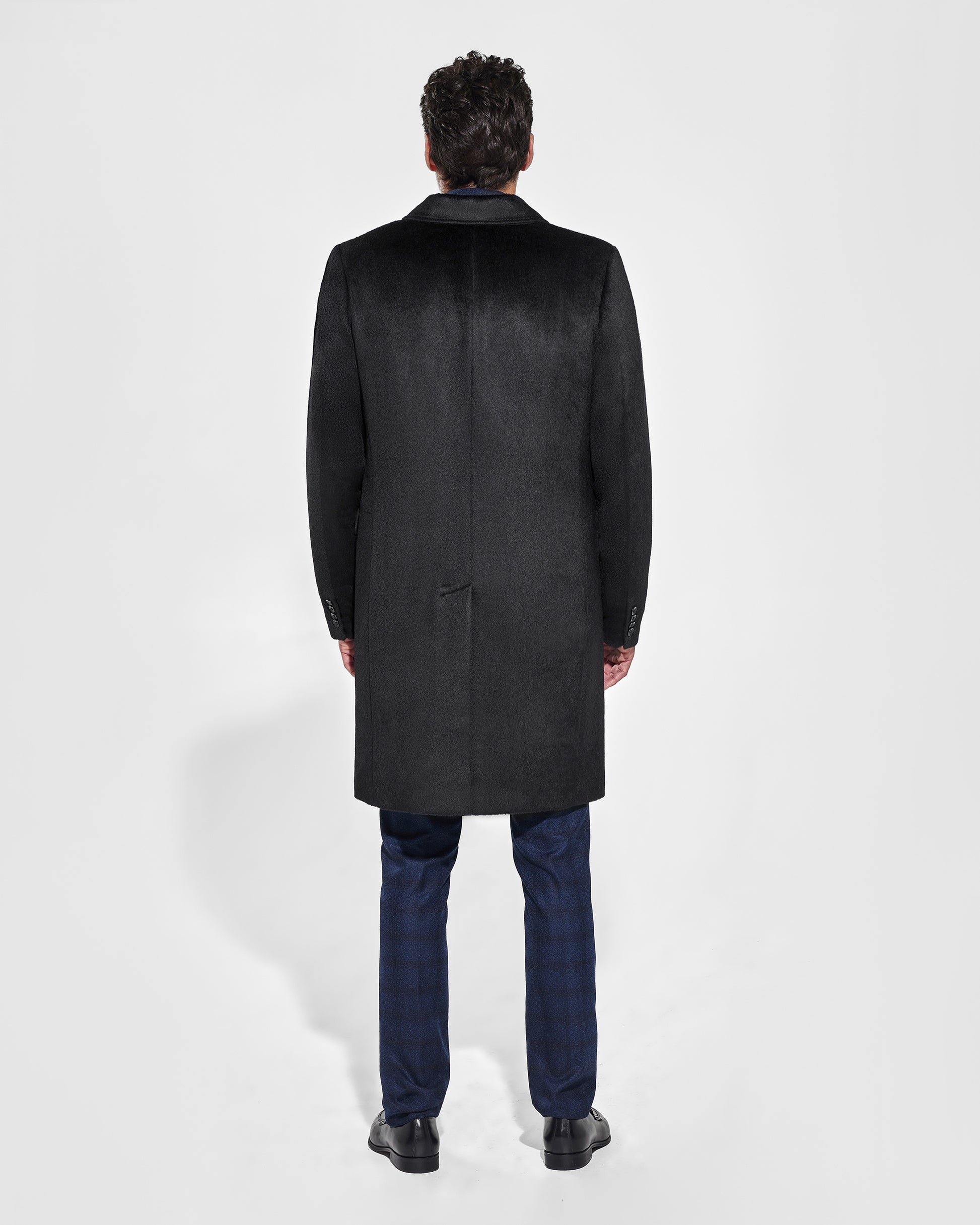 Sentaler Notched Lapel Black Overcoat in Suri Alpaca wool. Seen from back on male model, worn buttoned.
