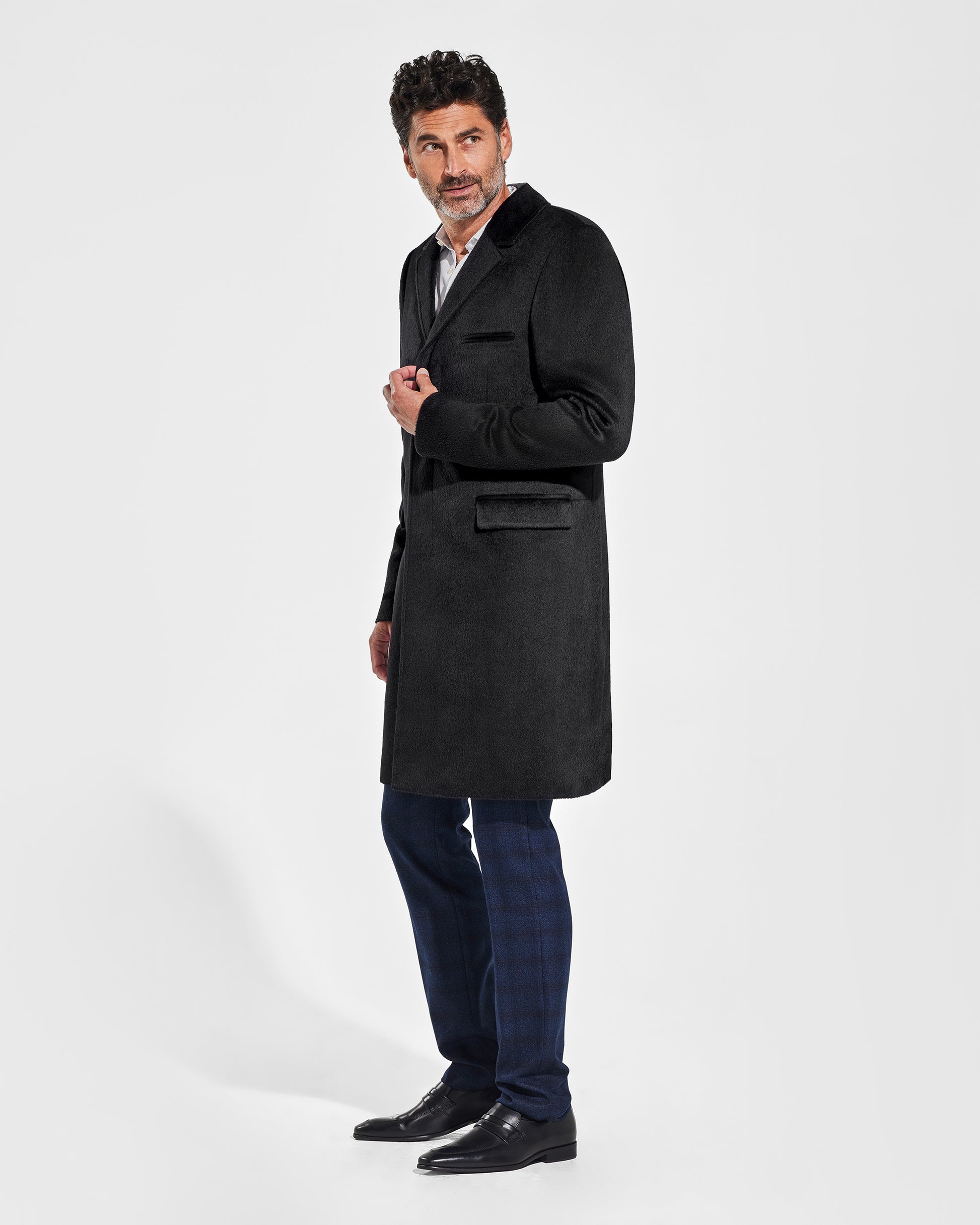 Sentaler Notched Lapel Black Overcoat in Suri Alpaca wool. Seen from side on male model, worn buttoned.