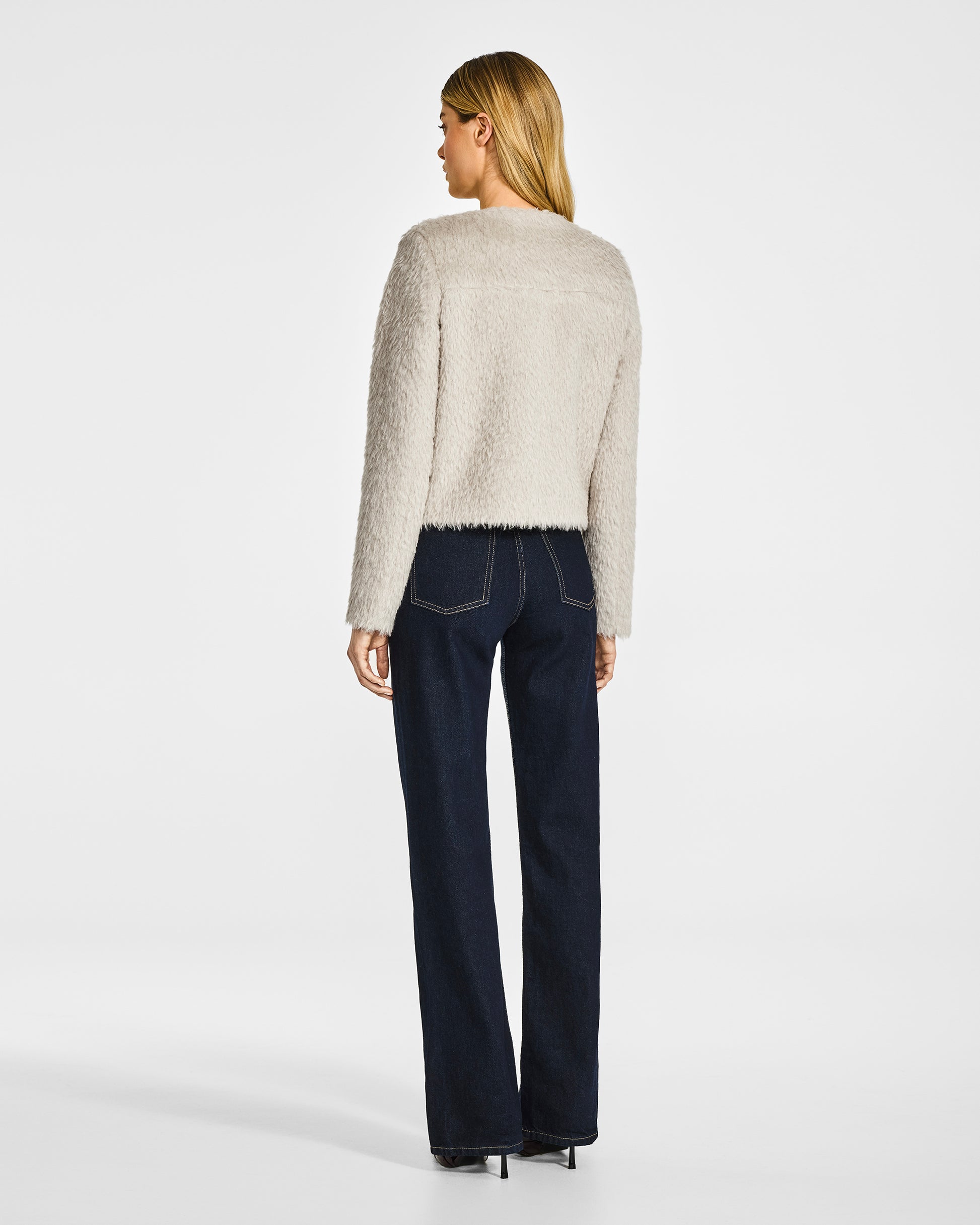 Back view of model wearing a Sentaler moto oat jacket made of textured suri alpaca wool, worn buttoned.