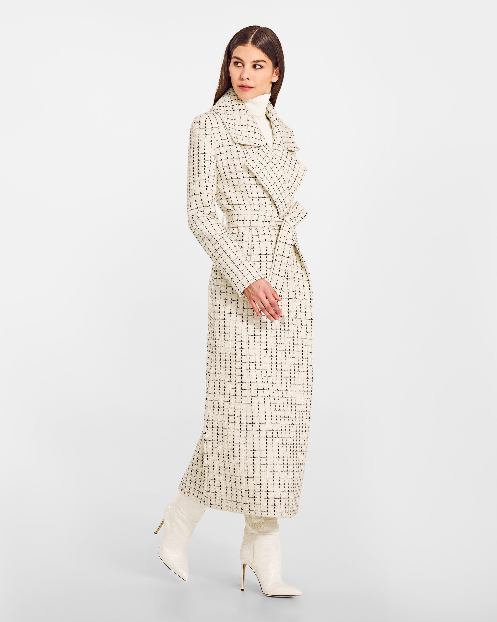 Side view of model wearing a Sentaler ivory check maxi coat made of suri alpaca wool, with a notched collar, worn belted.