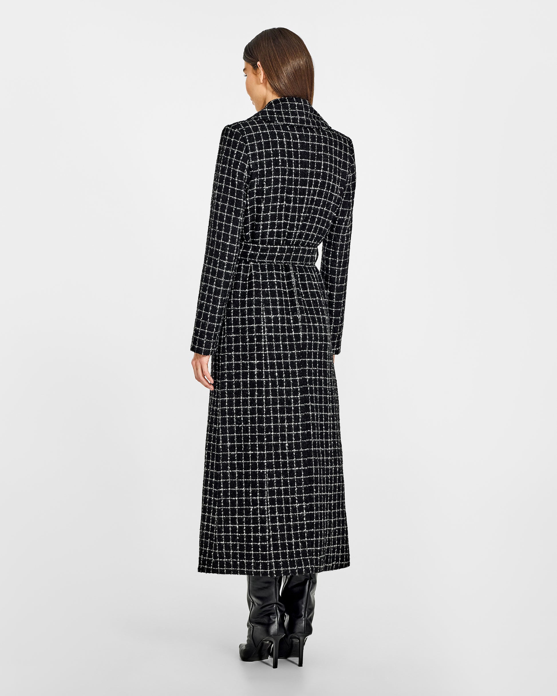 Back view of model wearing a Sentaler black check maxi coat made of tweed suri alpaca wool, with a notched collar, worn belted.
