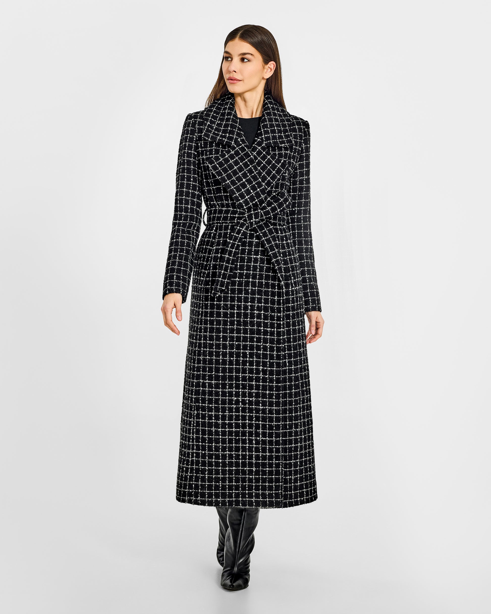 Front view of model wearing a Sentaler black check maxi coat made of tweed suri alpaca wool, with a notched collar, worn belted.