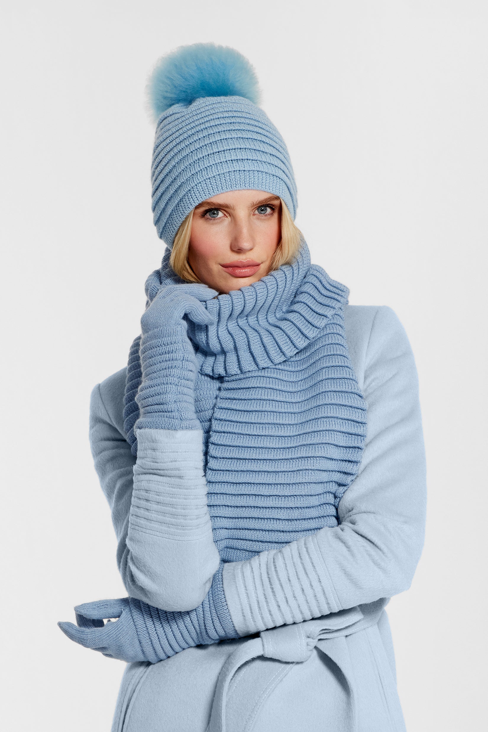 Front view close of model wearing Sentaler's signature powder blue ribbed hat, scarf, and gloves, paired with a matching powder blue coat.