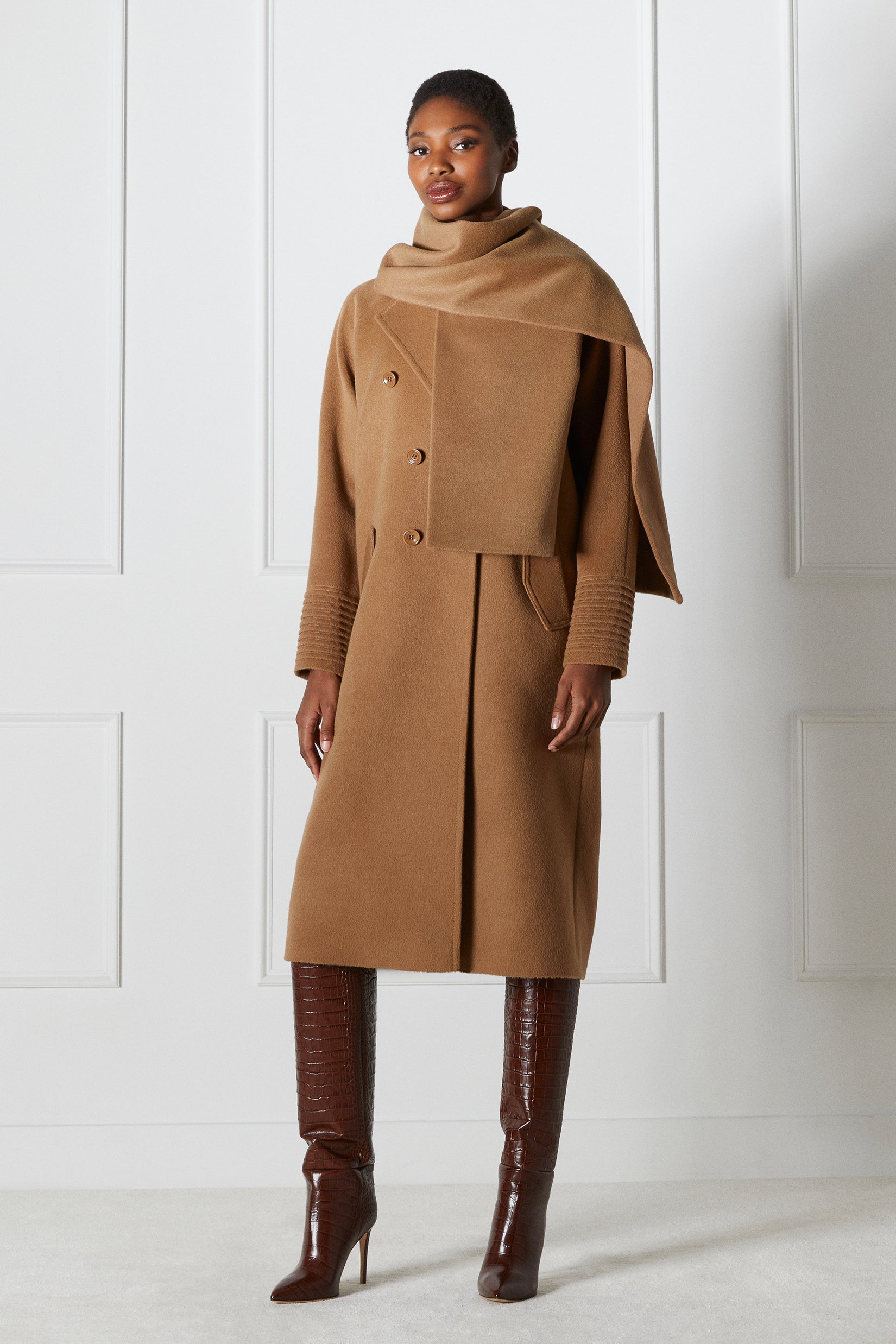 Side view of model wearing a Sentaler dark camel double breasted coat made of baby alpaca wool with a notched collar, worn with fabric scarf.