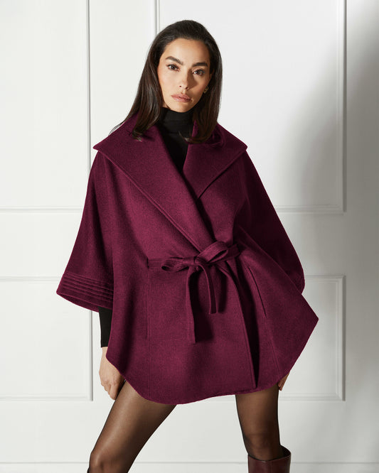Front view of model wearing a Sentaler cherry lacquer cape made of baby alpaca wool, with a shawl collar, worn belted.