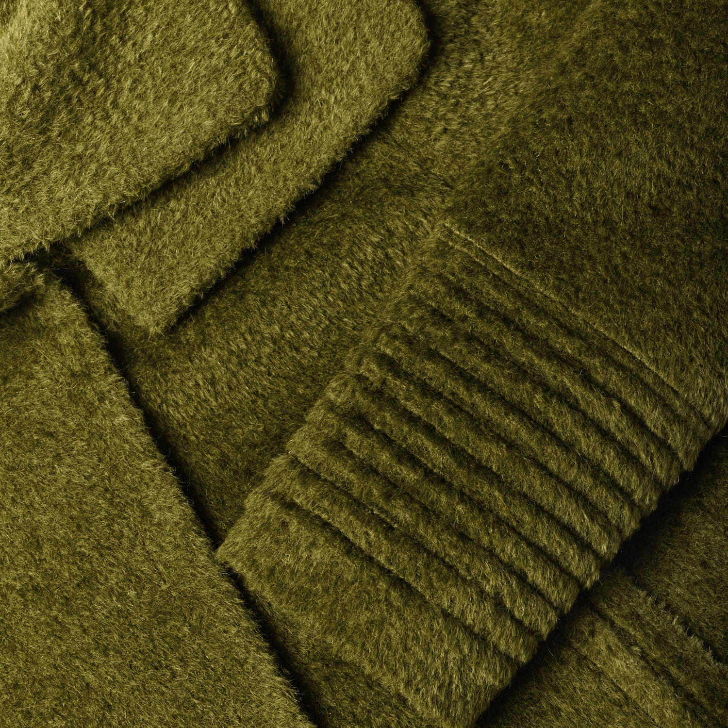Close-up of bouclé alpaca sea kelp green fabric texture with signature ribbed cuff.