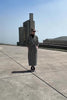 Video of a model wearing a Sentaler Black and White Houndstooth Tweed Suri Alpaca Long Raglan Sleeve Wrap Coat, with concrete architecture in the background.