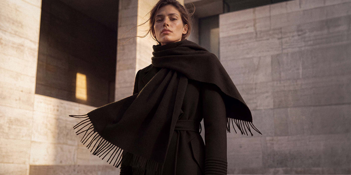 SENTALER Baby Alpaca Classic Scarf in Chocolate Brown. Worn wrapped over a belted coat, fringed ends falling forward.