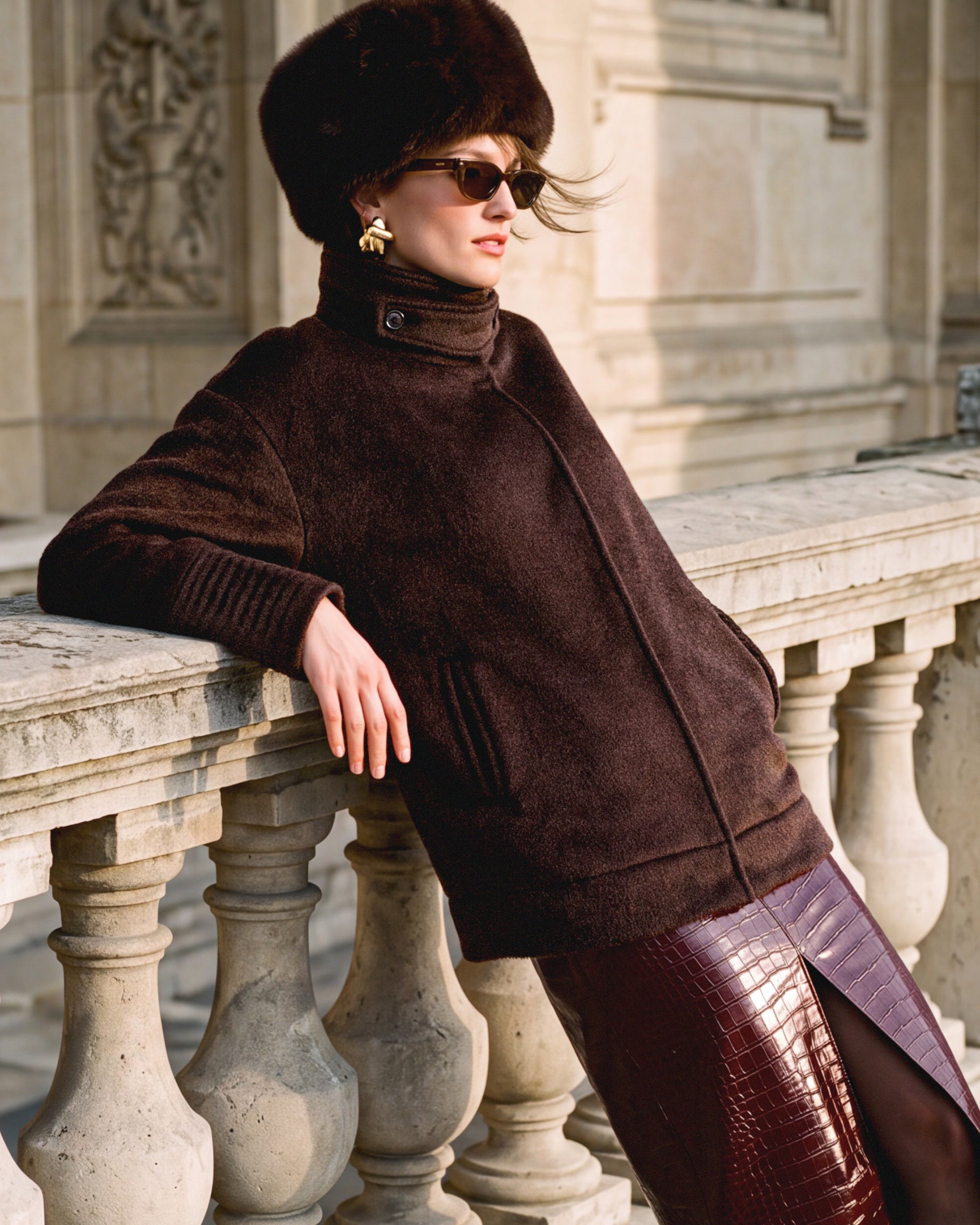 SENTALER Suri Alpaca Stand Collar Aviator Jacket in Chocolate Brown, worn by a female model leaning on a stone balustrade in Paris.