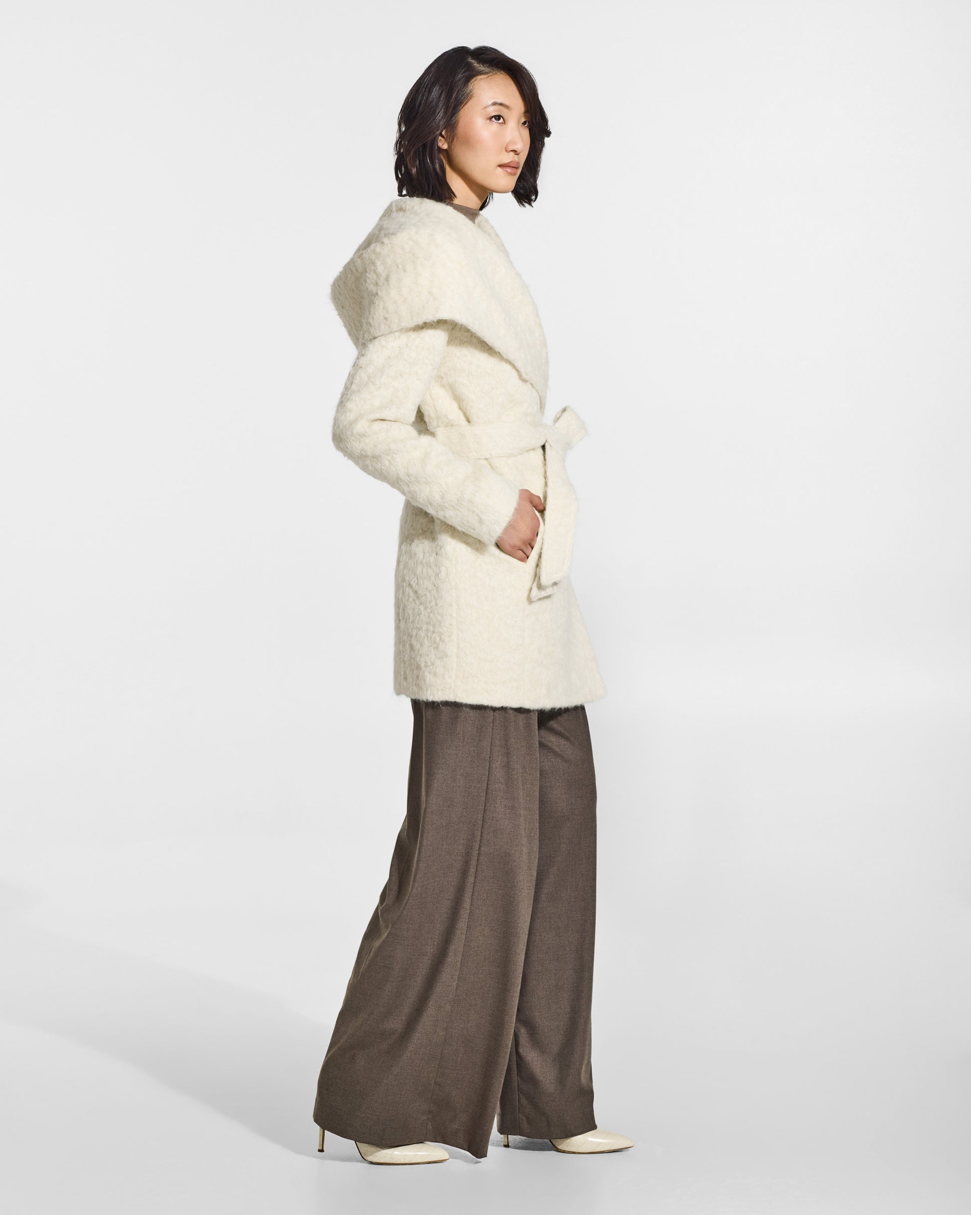 SENTALER Short Hooded Wrap Coat in Cloud White, Textured Suri Alpaca. Worn by a female model, side view, belted.