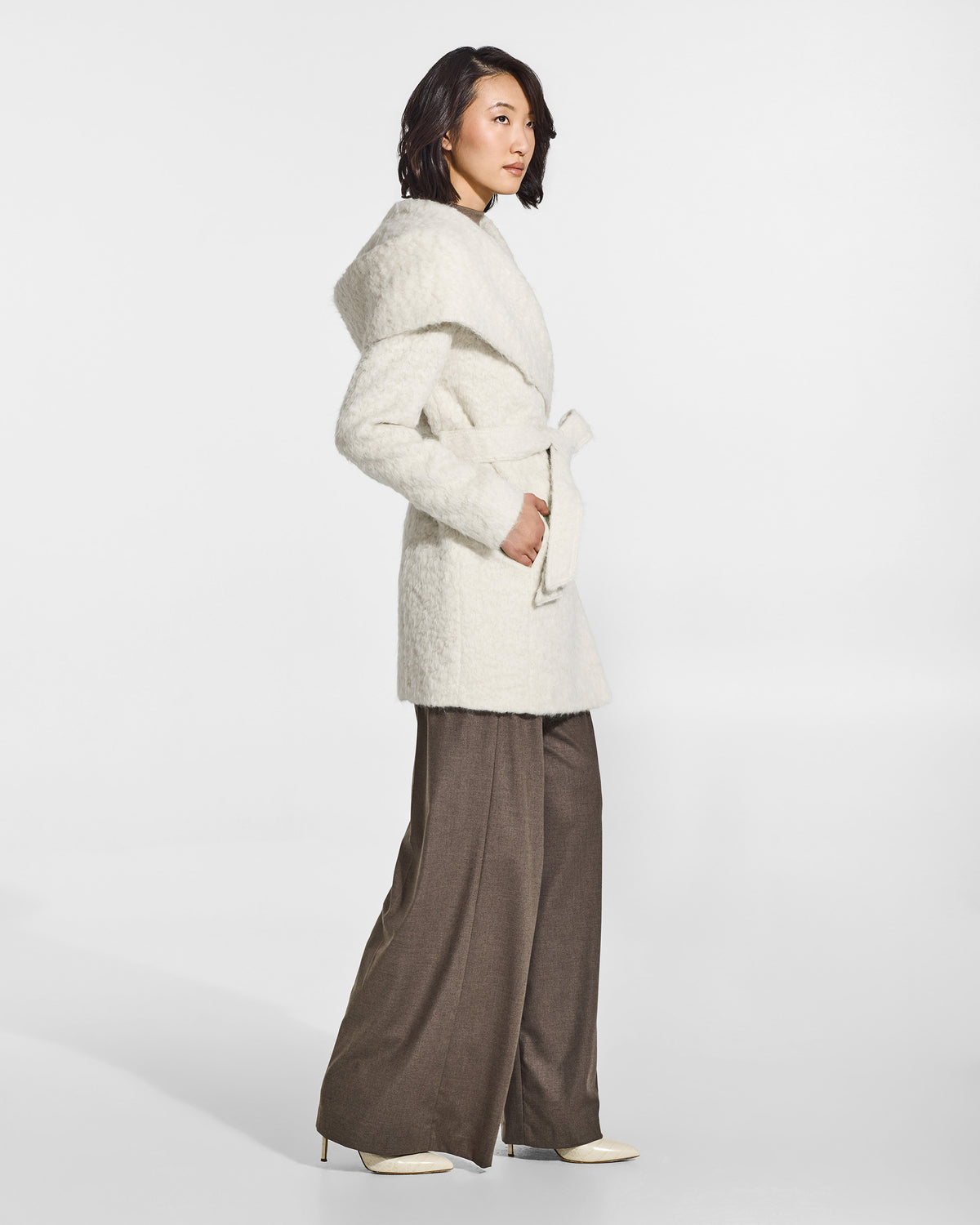 SENTALER Short Hooded Wrap Coat in Cloud White, Textured Suri Alpaca. Worn by a female model, side view, belted.