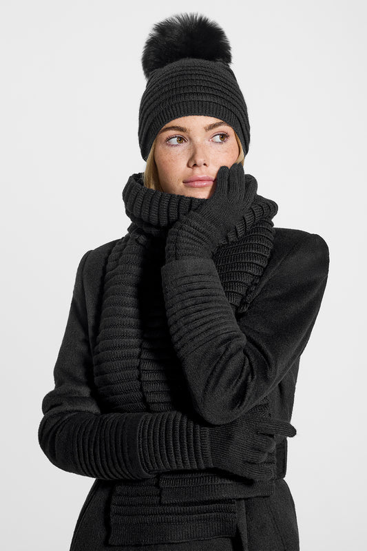 Sentaler Adult Ribbed Gloves, Adult Ribbed Hat with Oversized Fur Pompon, Adult Ribbed Scarf featured in Baby Alpaca and available in Black. Seen from front on model.