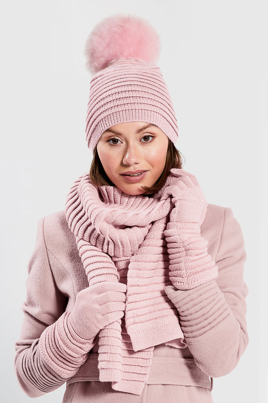 Sentaler Adult Ribbed Gloves, Ribbed Hat with Oversized Fur Pompon and Ribbed Scarf featured in Baby Alpaca and available in Pink. Seen from front above the waist on model.